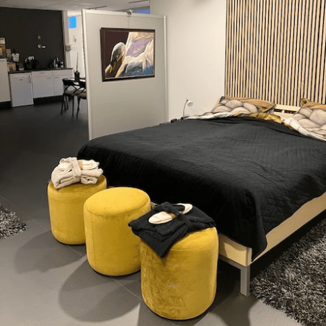 en luxe slaapkamer met een groot bed, zwarte en gouden accenten, zachte kussens en een open indeling met zicht op een kitchenette.